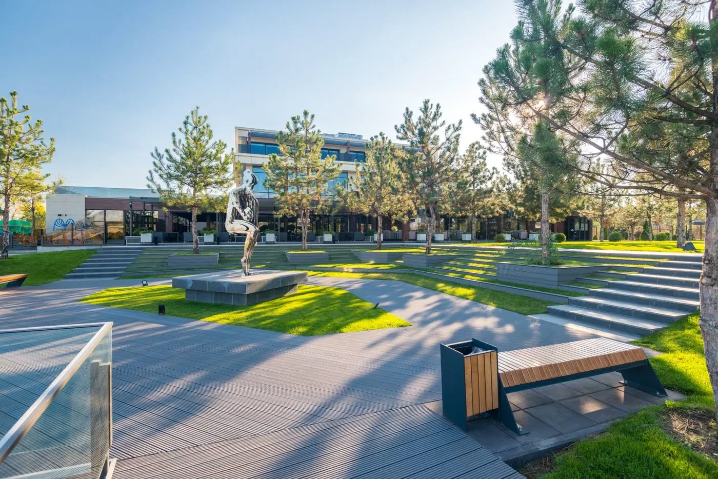 Kademeli çim alanlar, ahşap zemin ve banklarla düzenlenmiş kamusal park.